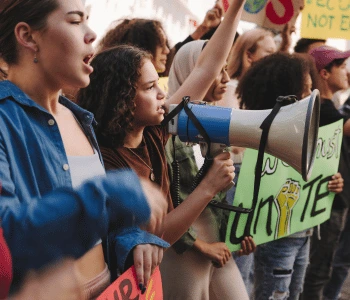 People at a protest using a megaphone, holding banners